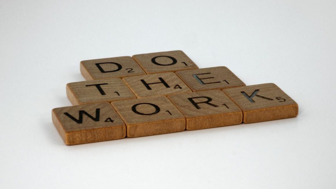 Motivational message spelled out with scrabble tiles on white background.